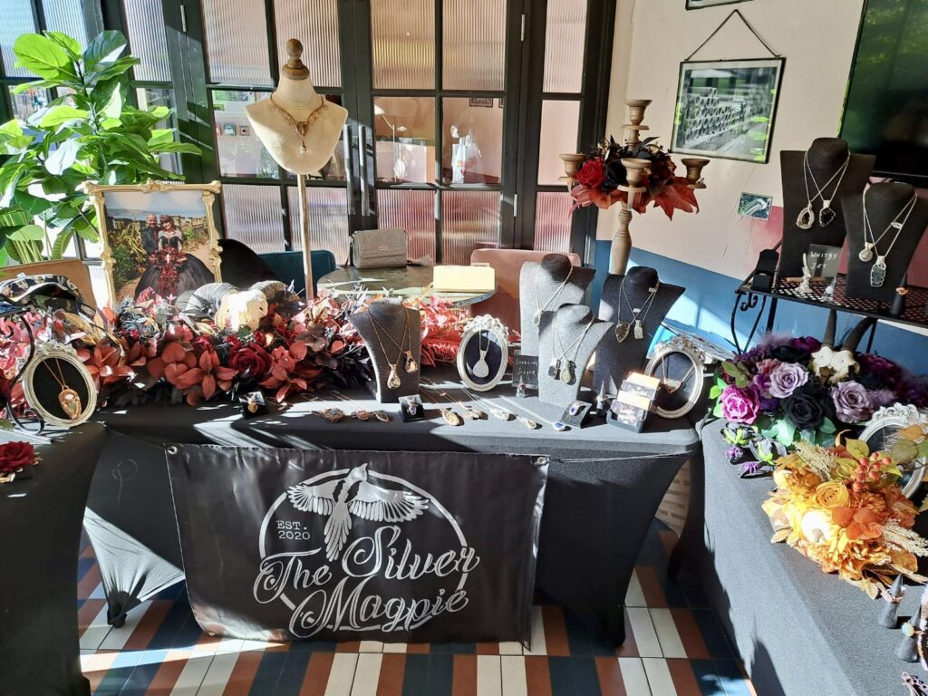A quirky, gothic styled stall with florals and black tablecloths
