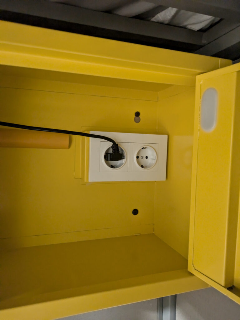 Interior of yellow locker, contains EU plug