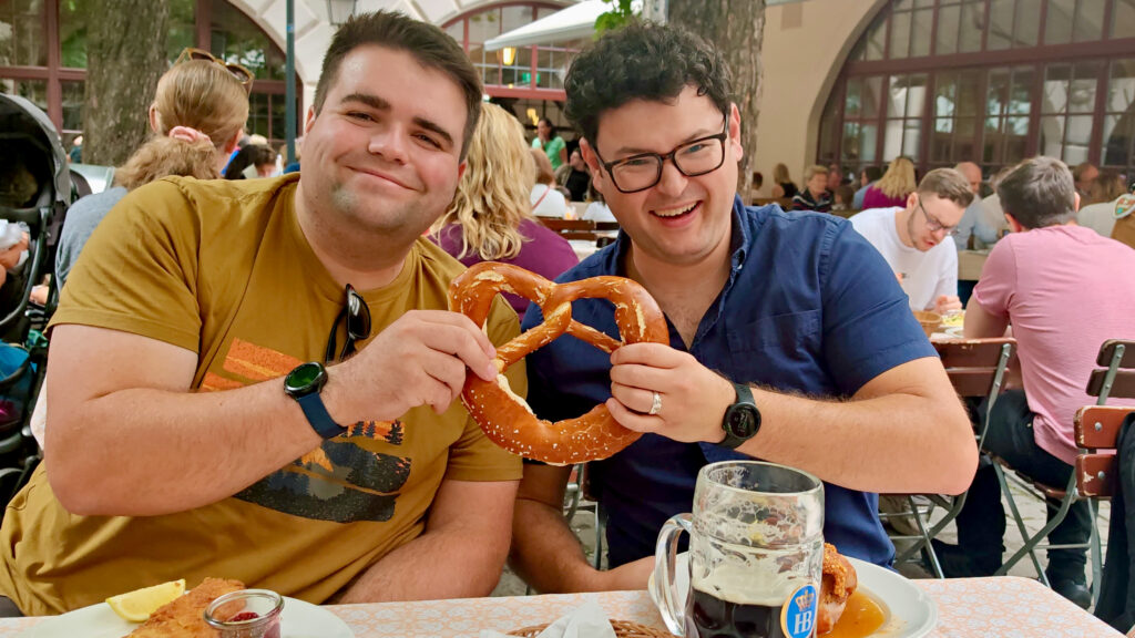 Richard and Tim are holding a pretzel and smiling