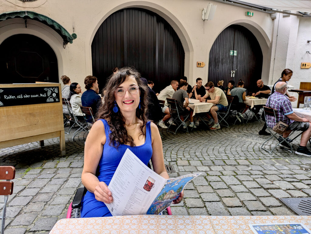 Georgina is seated in a wheelchair and holds the Hofbräuhaus exterior courtyard