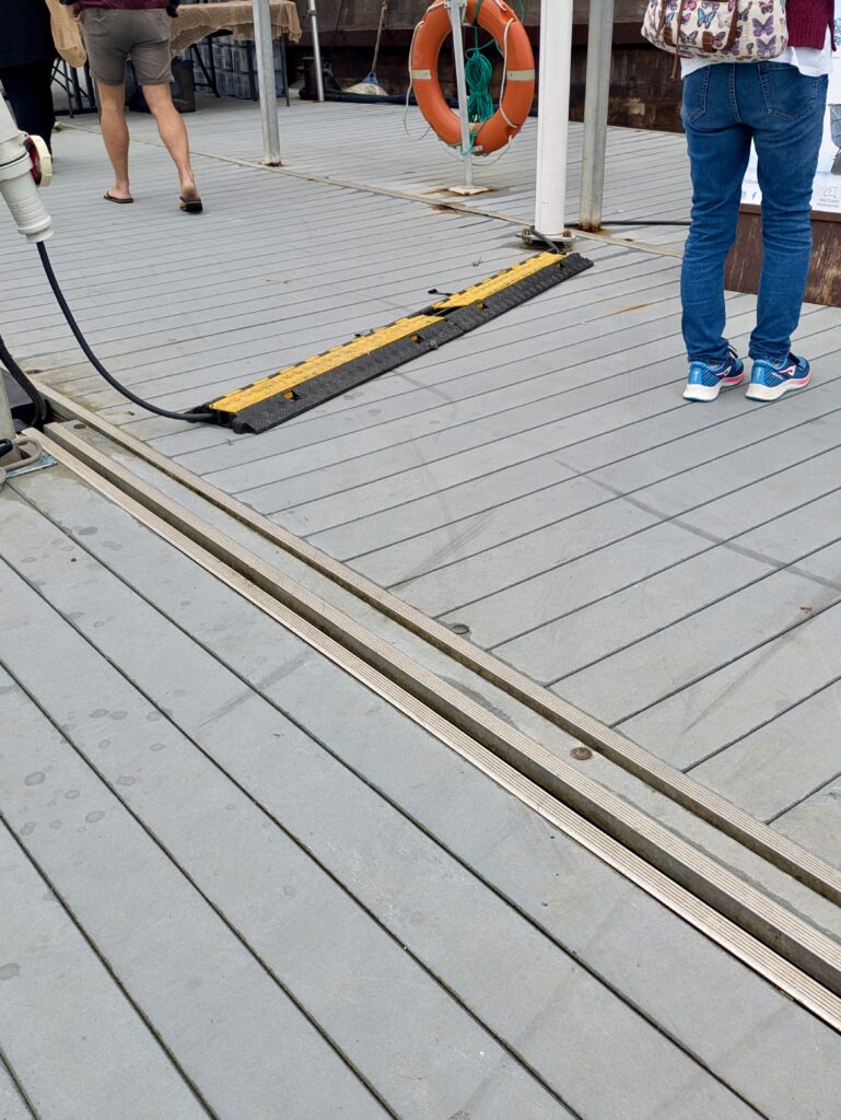 Grey decking at Cowes Royal Yacht Club Harbour with cables covered by safety ramp