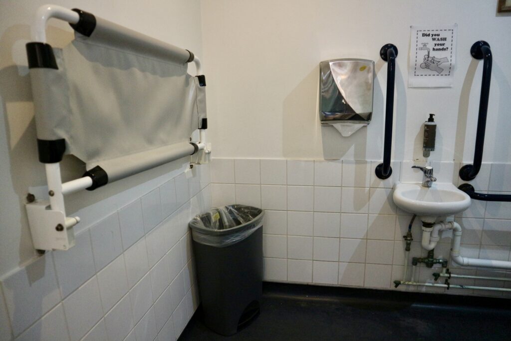 Baby changing mat and grab rails around sink in disabled toilet