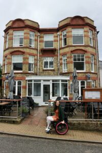 Beautiful red and yellow brick front of the Seaview Hotel in the Isle of Wight. Georgina is a wheelchair user and is seated in front of the building